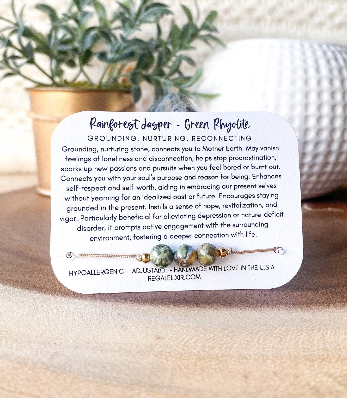a bracelet with a poem on it sitting next to a potted plant