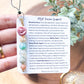 a person holding a bookmark with a flower on it
